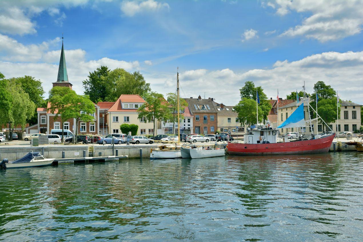 Blick auf den Hafen von Neustadt in Holstein mit Segelbooten und historischer Architektur – attraktive Wohnlagen mit Immobilienmakler Neustadt in Holstein entdecken.